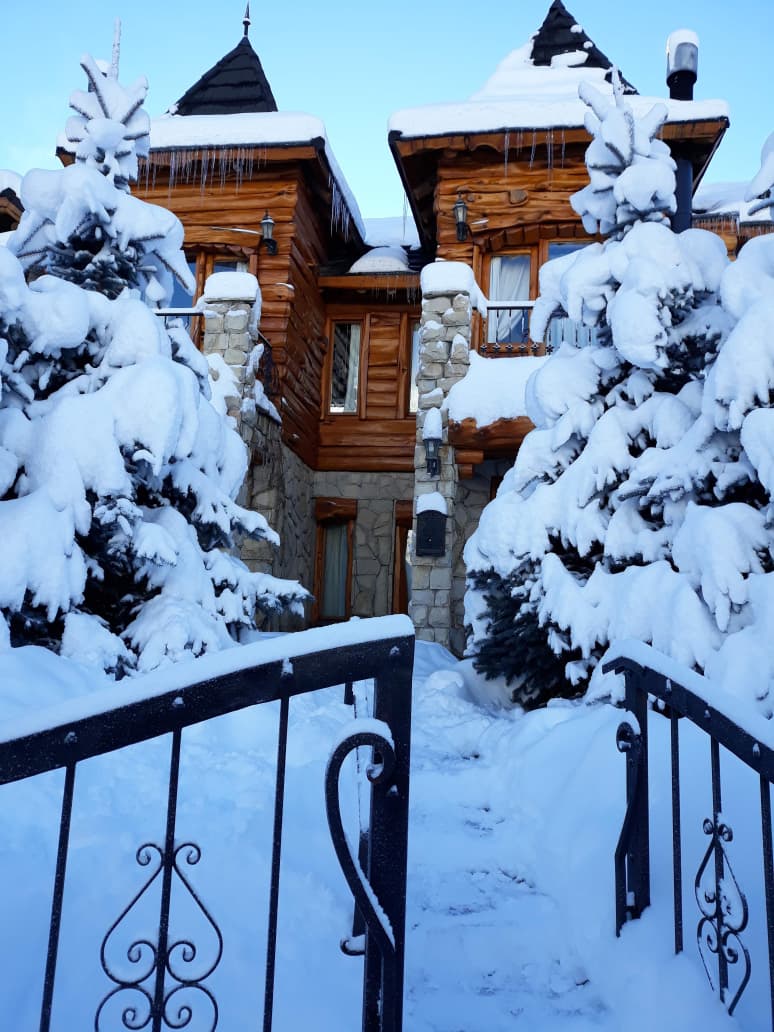 Entrada a la cabaña entre árboles cubiertos de nieve